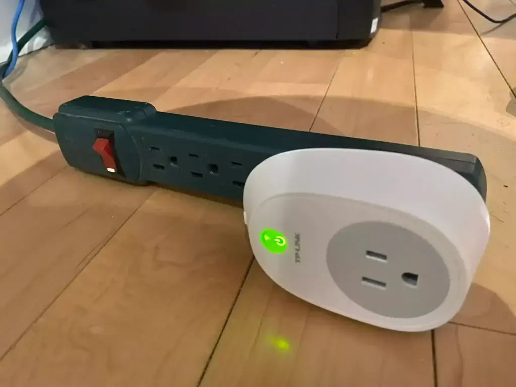 A smart plug connected to a power strip instead of directly plugging it into a wall outlet